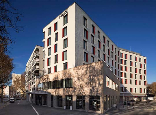 Straßenansicht des großen und modernen Hotels bei strahlend blauem Himmel.