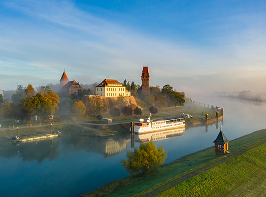 Atemberaubende Aussicht auf das Schloss von der anderen Uferseite, mit einem großen Rundfahrtschiff davor