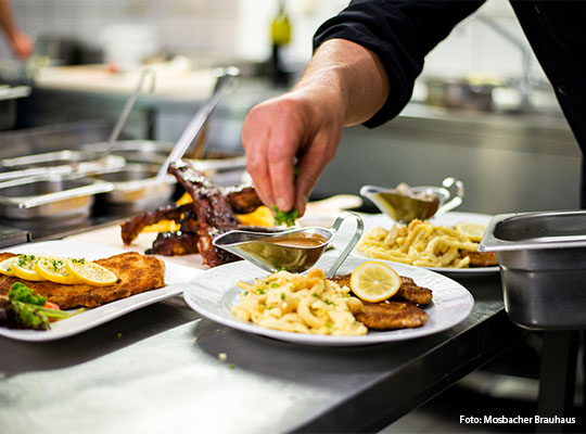 Hand, welche Kräuter über Schnitzel verteilt